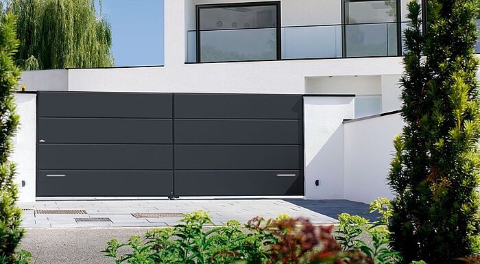 Portail aluminium battant Lucco équipé de 4 cassettes horizontales et laqué en gris anthracite (RAL 7016FS).  Ce portail est doté de 2 bandes LEDs qui s'allument en éclairage d'ambiance pendant la soirée et clignotent lorsque le portail est en mouvement.  Pour un plus grand confort d'utilisation, les clients ont opté pour un portail motorisé.  Ce portail aluminium électirque est installé près de Strasbourg, dans le Haut Rhin (67).